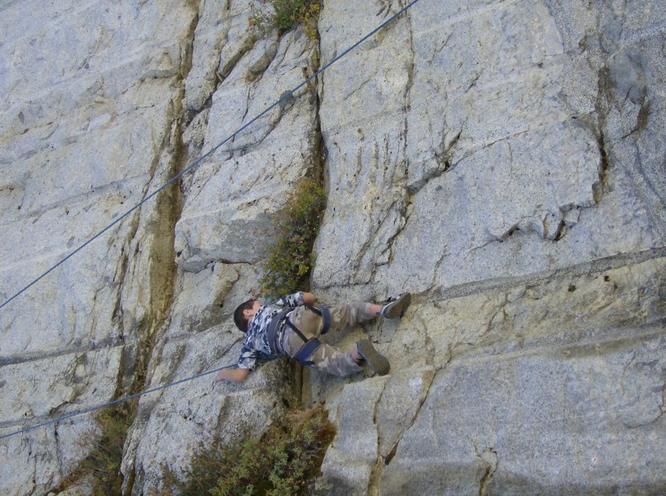 Rock climber on a cliff face with climbing ropes