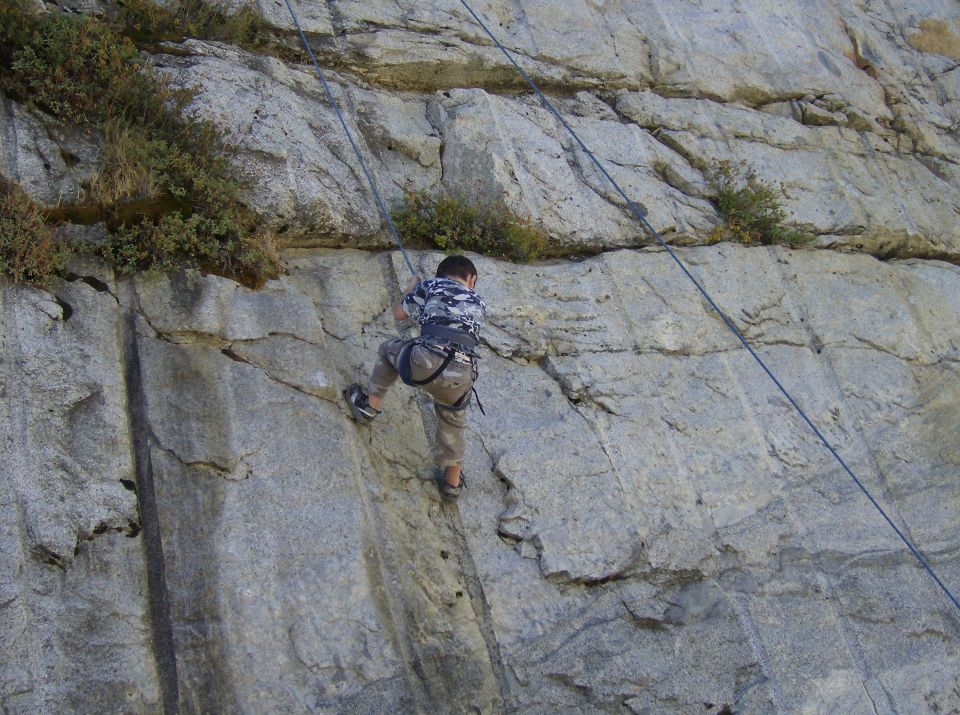 Person rock climbing on a large cliff face with ropes and harnesses