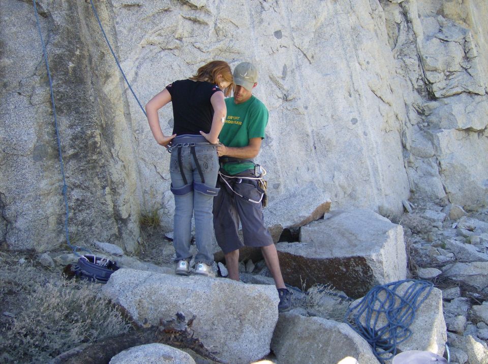 Two people getting ready to rock climb, one is adjusting the other's harness