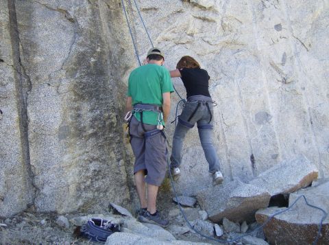 1986 Ford Bronco - Two individuals are engaged in rock climbing activities on a large granite formation.