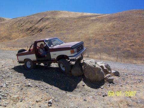 1991 Ford Bronco - This 1991 Ford Bronco is navigating a rocky trail with its driver visible.