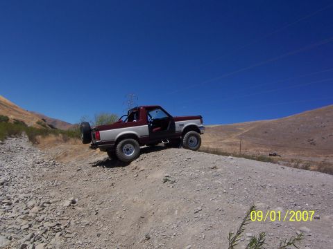 1991 Ford Bronco - A 1991 Ford Bronco is parked on a rocky incline under a clear blue sky.
