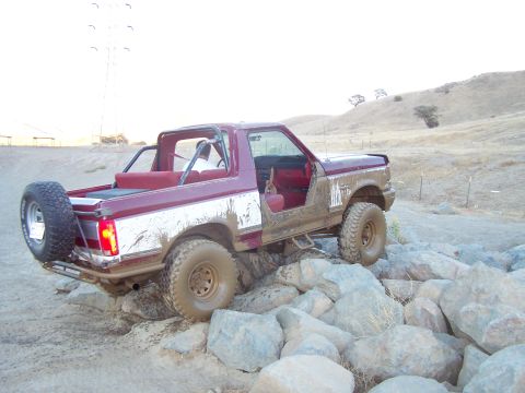 1991 Ford Bronco - This red and white Ford Bronco navigates a rocky trail, its off-road capabilities.