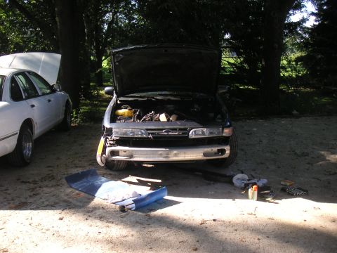 1996 Ford Crown Victoria - Two Ford Crown Victorias are parked outdoors, one with its hood open and front bumper removed.
