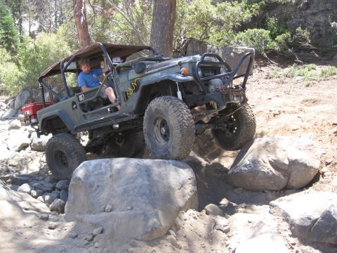 1994 Ford Bronco - An off-road vehicle navigates a challenging rocky terrain with a driver inside.
