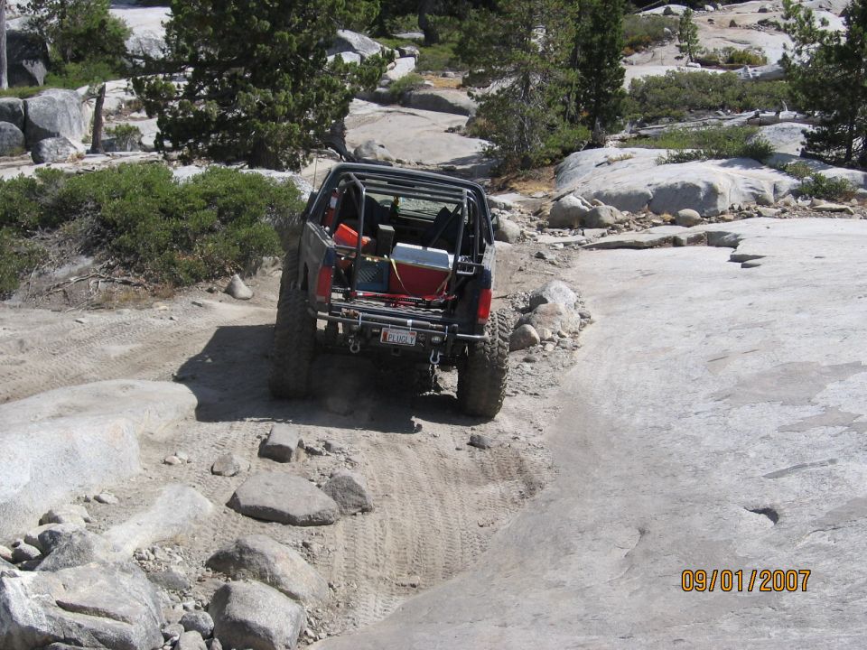 Topless caged 4x4 with PLUG UGLY plate crawling over bare granite slabs