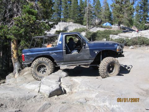 1994 Ford Bronco - 1994 Ford Bronco tackling a challenging rock crawl course on a sunny day.