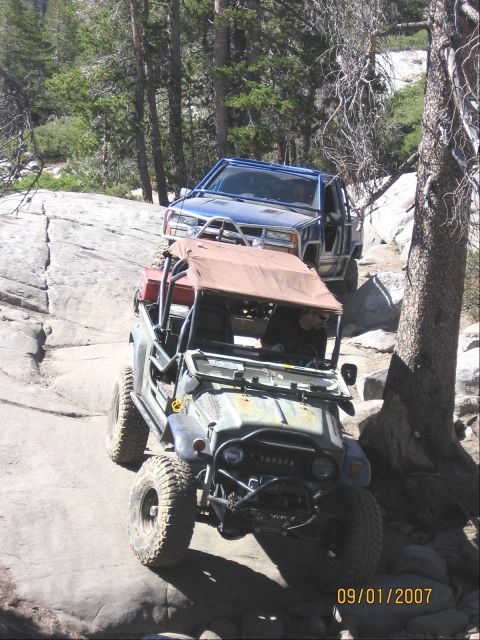 1994 Ford Bronco - Two off-road vehicles tackle a challenging rocky path on a sunny day.
