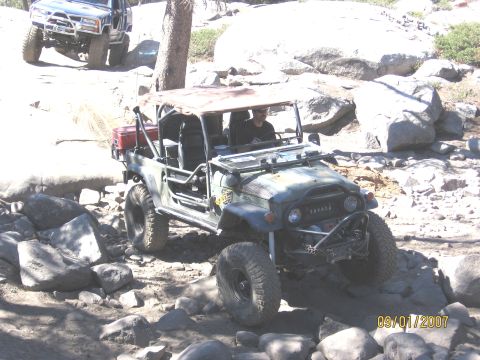 1994 Ford Bronco - Modified Toyota Land Cruiser FJ40 navigating a rocky trail, with another vehicle in the background.