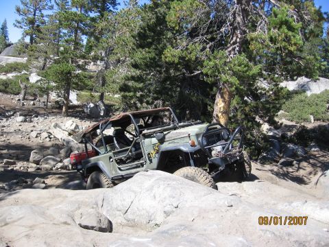 1994 Ford Bronco - This off-road vehicle is navigating a challenging rocky path in a wooded area.