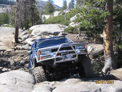 1994 Ford Bronco - A blue off-road vehicle is shown navigating a challenging rocky trail.