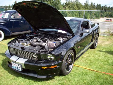 1997 Ford Mustang - Black Ford Mustang with hood open, displaying its engine and silver racing stripes.