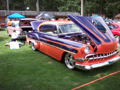 1997 Ford Mustang - A two-tone orange and purple classic car is displayed with its hood open at an outdoor car show.