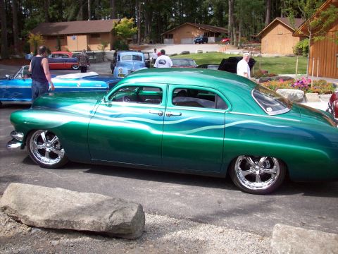 1997 Ford Mustang - A customized sedan with a unique green and blue paint job is parked outdoors.