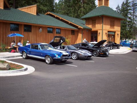 1997 Ford Mustang - A blue 1967 Ford Mustang Shelby GT500 is parked in front of a wooden building with other cars.