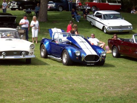 1997 Ford Mustang - A blue convertible with white racing stripes is displayed at an outdoor car show.