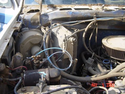 1989 Ford Bronco - The engine bay of a vehicle, showing various hoses, the air filter, and a date stamp of MAY 5 2003.