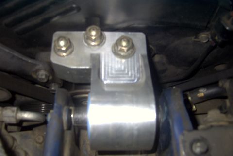 1994 Dodge Stealth - This is a close-up view of an aftermarket motor mount, likely made of aluminum, with visible bolts and a textured surface.
