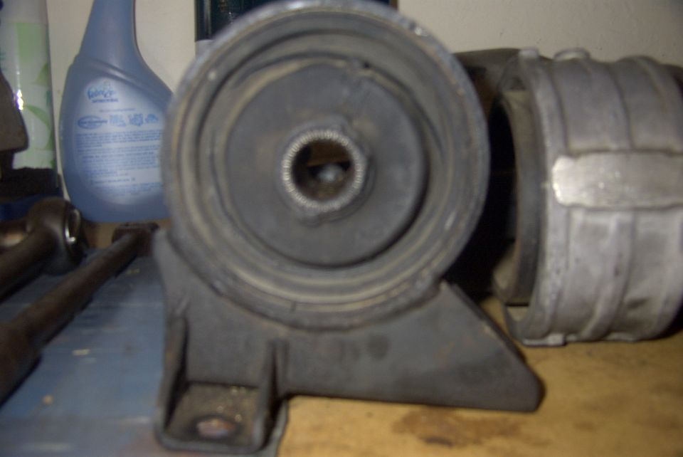 Close-up of a car engine mount with a bottle of cleaner in the background