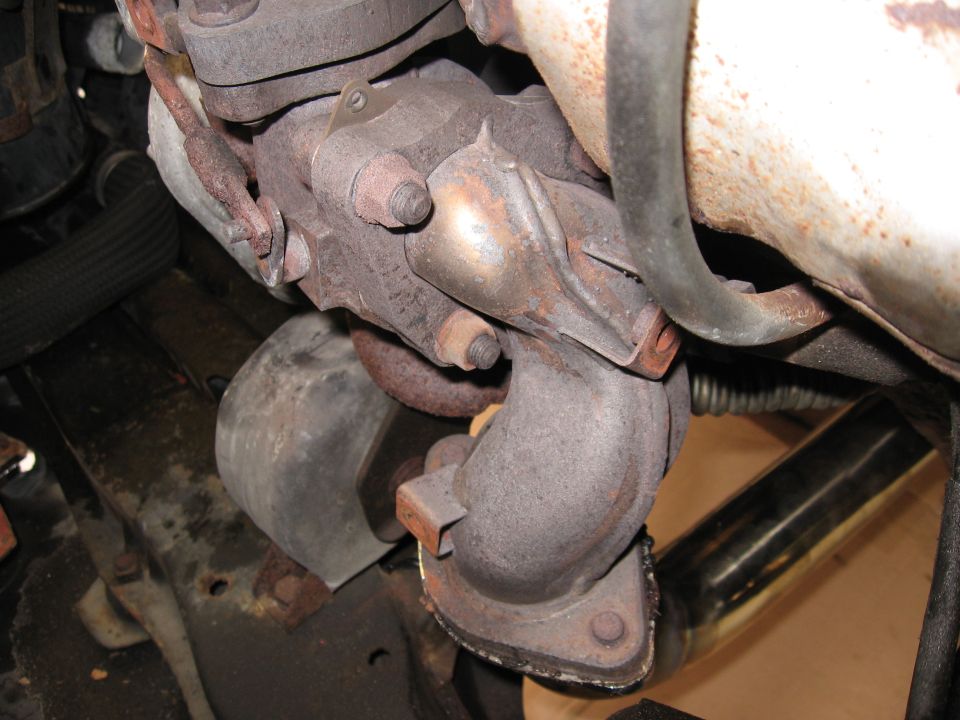Turbocharger and exhaust manifold assembly with rusted metal components and a black hose