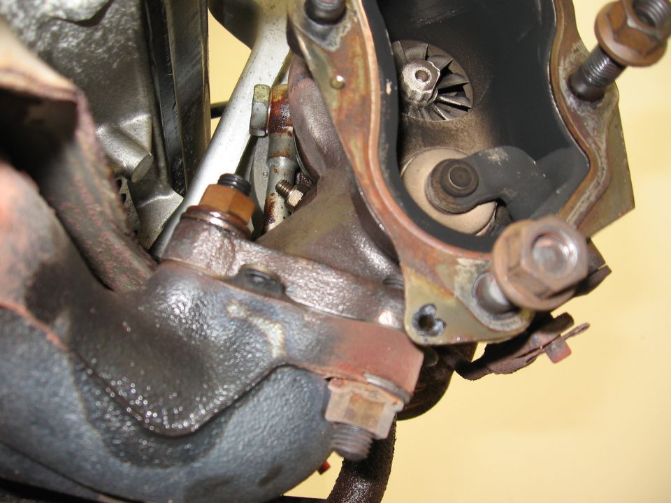Turbocharger turbine wheel and exhaust manifold with visible oil residue and rust