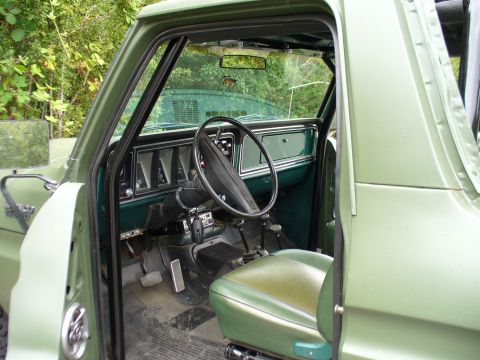 1978 Ford Bronco - The interior of a classic truck is shown, a green dashboard and seats.