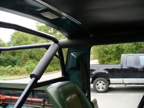 1978 Ford Bronco - The interior of a vehicle shows a roll cage and a seat, with a pickup truck visible through the window.