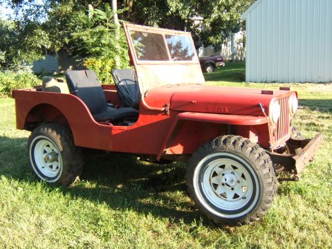 1946 Jeep CJ5 - This vintage Willys Jeep is shown from a three-quarter front angle, parked outdoors on a grassy area.
