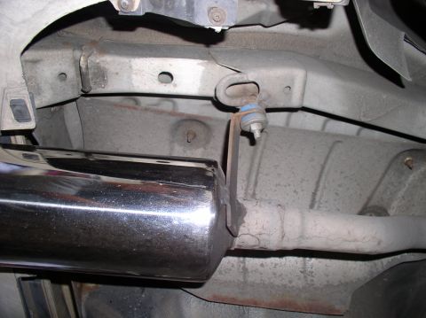 1994 Ford Probe - Close-up view of a vehicle's exhaust system, showing a chrome muffler tip and its mounting bracket.