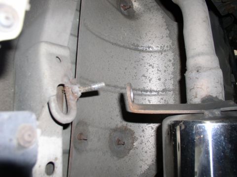 1994 Ford Probe - Undercarriage view of a rusted bolt and bracket, likely part of the exhaust system mounting.