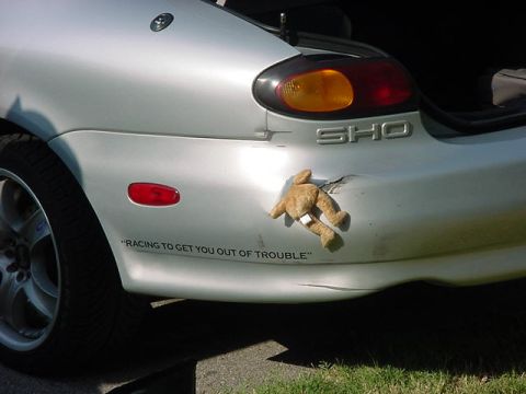 1997 Ford Taurus - Rear view of a silver 1997 Ford Taurus SHO showing damage and a humorous sticker.