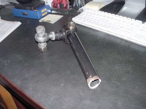 1979 Ford Bronco - A close-up view of a tie rod end with a ball joint and threaded rod, resting on a dark surface.
