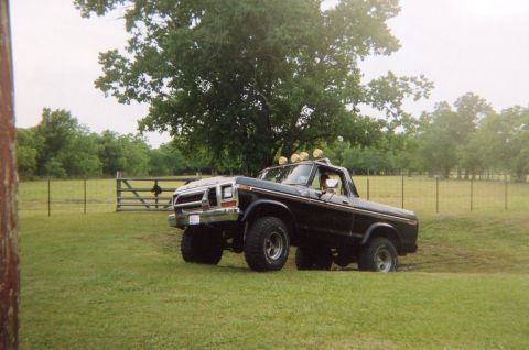 1978 Ford Bronco - A black 1978 Ford Bronco is shown from a three-quarter front angle in a grassy outdoor setting.
