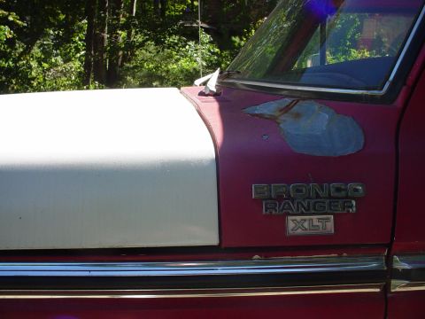 1978 Ford Bronco - Close-up of a 1978 Ford Bronco Ranger XLT fender showing the emblem and some paint damage.