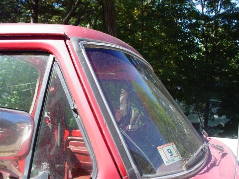 1978 Ford Bronco - Interior view of a 1978 Ford Bronco, with red seats visible through the dusty windshield.
