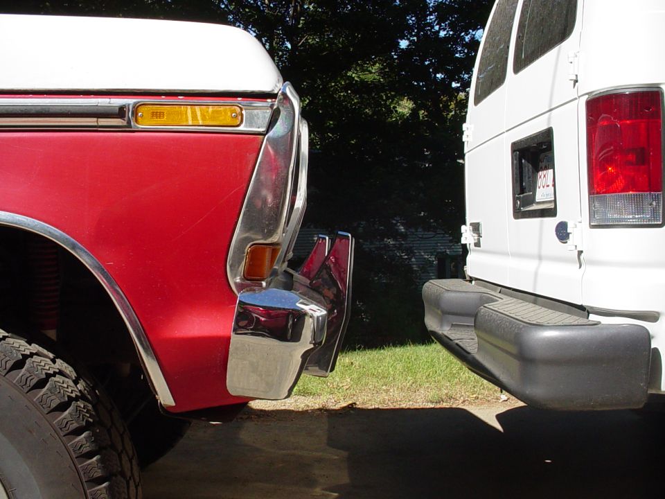 Close-up of a red truck's front end next to a white van
