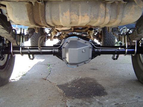 1978 Ford Bronco - The underside of a vehicle shows a differential cover and leaf spring suspension system.