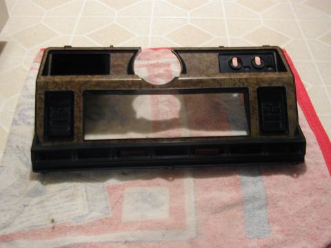 1986 Ford Bronco - This dashboard trim piece shows a wood grain finish and openings for a radio and air vents.