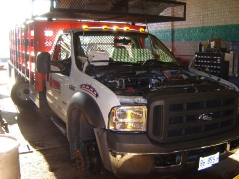 1992 Ford Bronco - This white Ford truck with a red stake bed is in a garage with its hood open, possibly for repairs or maintenance.