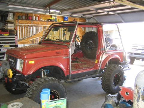 1987 Suzuki Samurai - This modified 1987 Suzuki Samurai features a custom exo cage and aggressive off-road tires, ready for adventure.