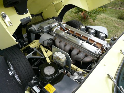 1975 Ford Ranchero - The engine bay of a yellow classic car, a V12 engine with triple carburetors, is shown with the hood open.