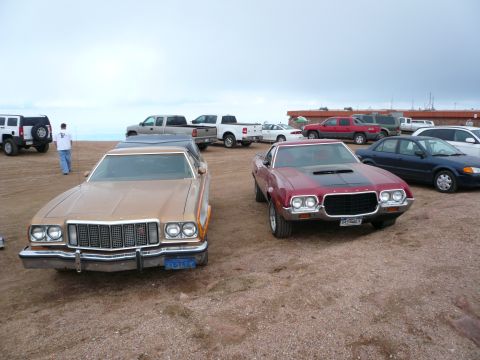 1975 Ford Ranchero - Two classic Ford Rancheros are parked side-by-side on a dirt lot under an overcast sky.
