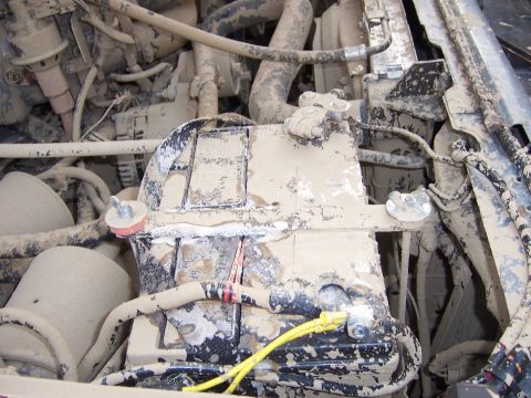 1991 Ford Bronco - The engine bay of a vehicle is heavily coated in mud, obscuring most details.