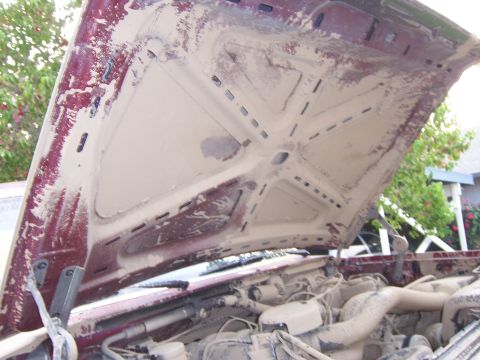 1991 Ford Bronco - The underside of the hood and engine compartment are heavily coated in dried mud, obscuring details.