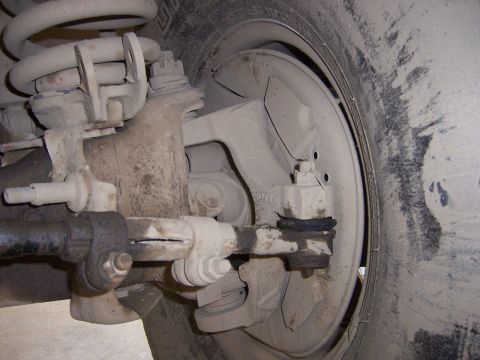 1991 Ford Bronco - Detail of the front suspension and wheel assembly, showing steering components and brake drum.