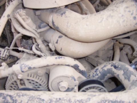 1991 Ford Bronco - Close-up of engine components, including hoses and alternator, obscured by dust.