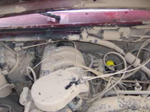 1991 Ford Bronco - The engine bay is heavily covered in dust and dirt, obscuring many details of the mechanical components.