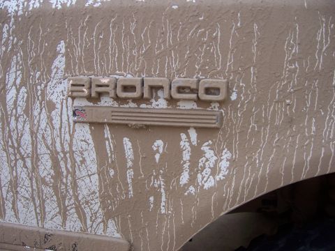 1991 Ford Bronco - Mud covers the Bronco emblem on the fender of a 1991 Ford Bronco.