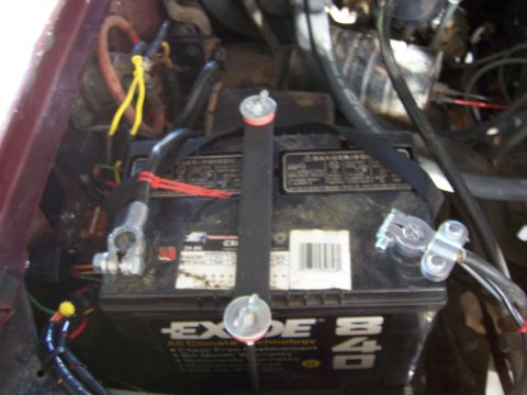 1991 Ford Bronco - Close-up of a vehicle battery and its surrounding engine bay components.