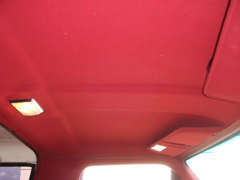 1991 Ford Bronco - The red fabric headliner of a vehicle is visible, along with two interior dome lights and a sun visor.